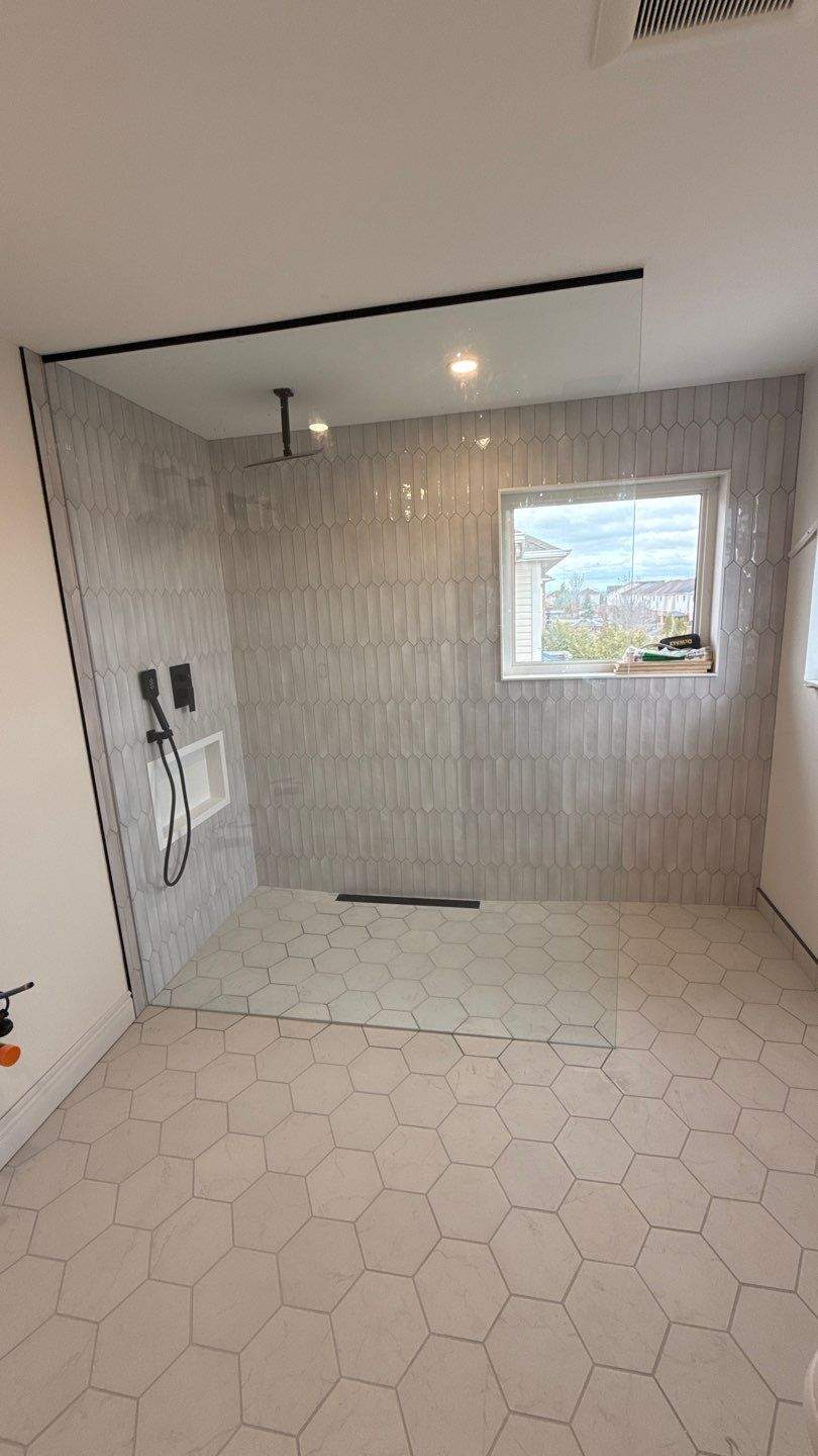 Finished curbless shower with single large glass panel